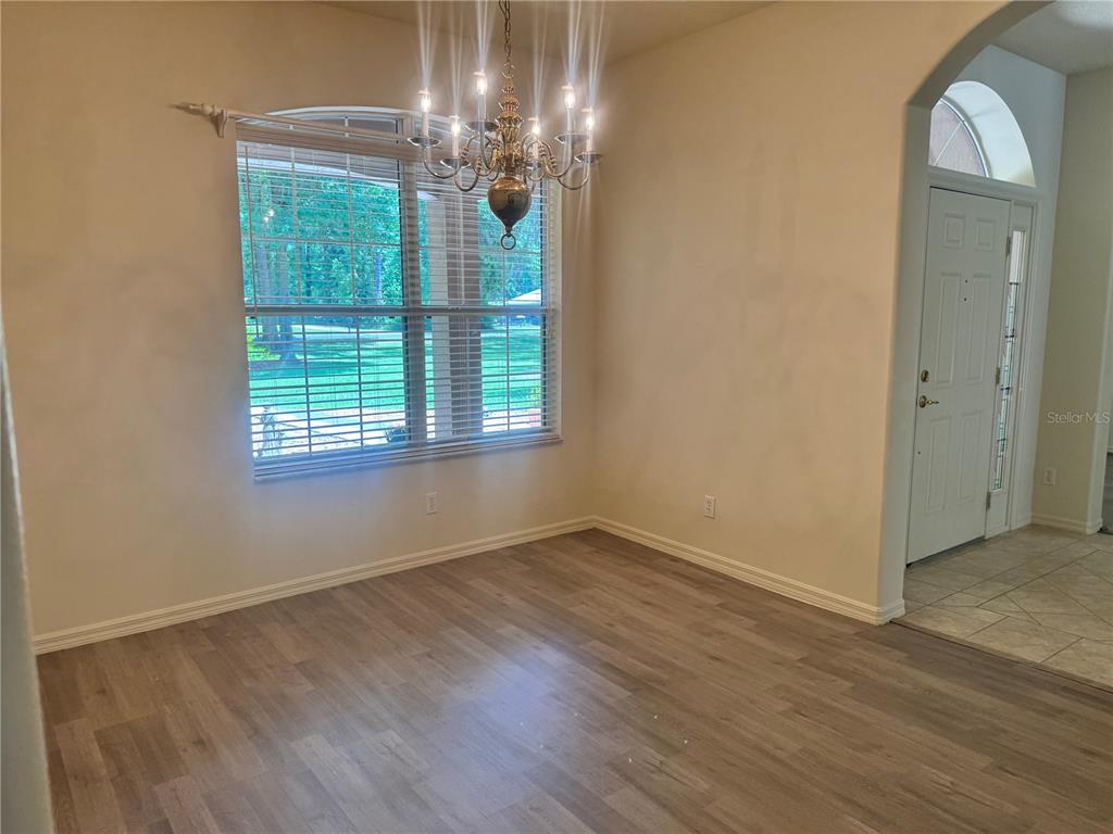 11145 Northwest 17th Court Road Ocala, FL 34475 - Photo 28 of 59 an empty room with wooden floor chandelier and windows