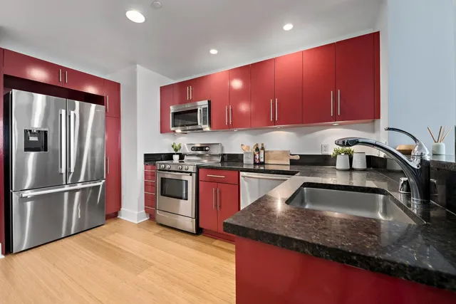 a kitchen with stainless steel appliances granite countertop a stove top oven a refrigerator and a microwave