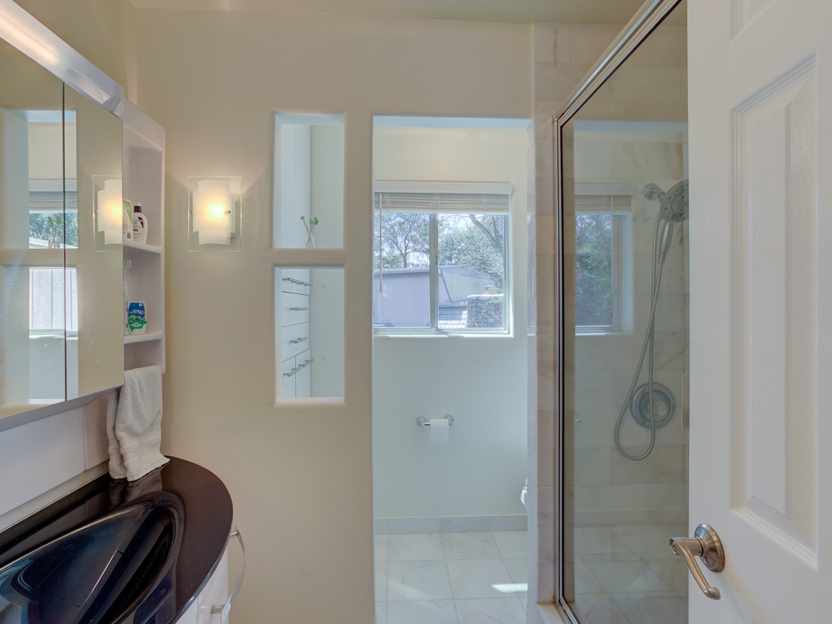 710 Castle Ridge Road, Unit B Austin, TX 78746 - Photo 23 of 27 A well-lit bathroom features a glass-enclosed shower and a modern vanity.