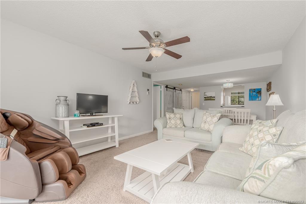 5433 Southeast Miles Grant Road, Unit 203 Stuart, FL 34997 - Photo 5 of 31 a living room with furniture and a flat screen tv