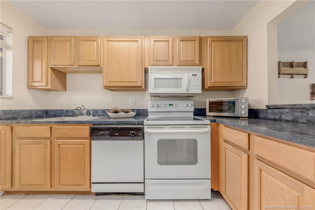 5433 Southeast Miles Grant Road, Unit 203 Stuart, FL 34997 - Photo 8 of 31 a kitchen with stainless steel appliances granite countertop white cabinets sink and a granite counter top