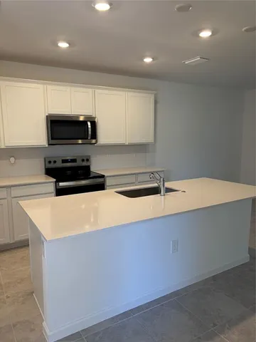 a kitchen with stainless steel appliances a stove a sink a microwave and a refrigerator