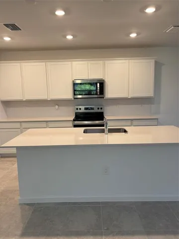 a kitchen with kitchen island a sink stainless steel appliances and cabinets