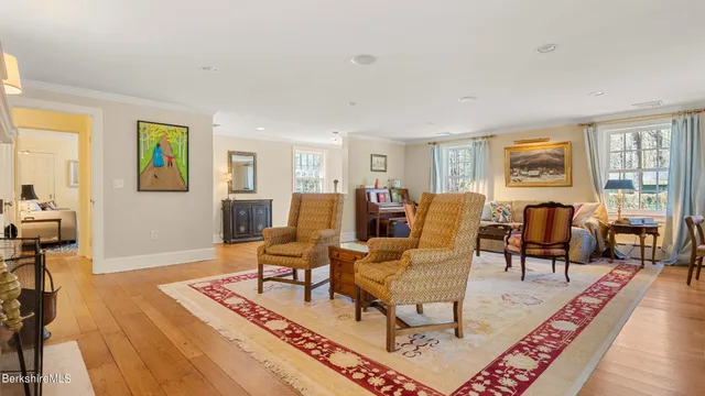 a living room with furniture two large windows with wooden floor