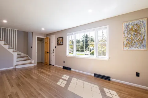 a view of an empty room with wooden floor and a window