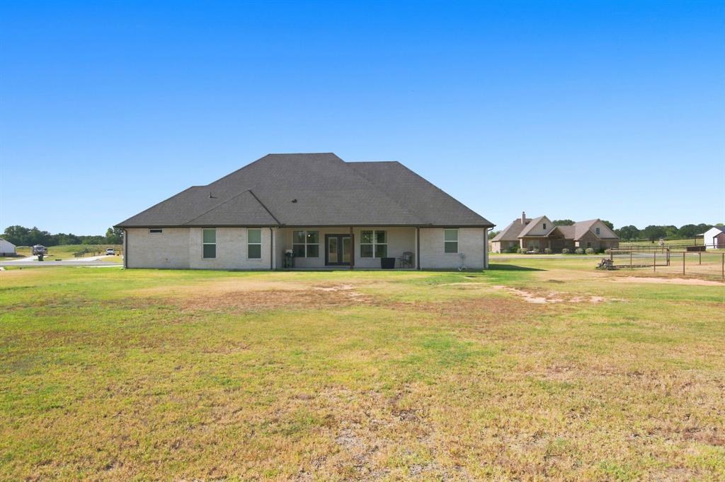 121 Friendship Way Boyd, TX 76023 - Photo 36 of 38 Expansive backyard featuring a light brick exterior, dark gabled roof, covered patio, and dual glass-paned doors