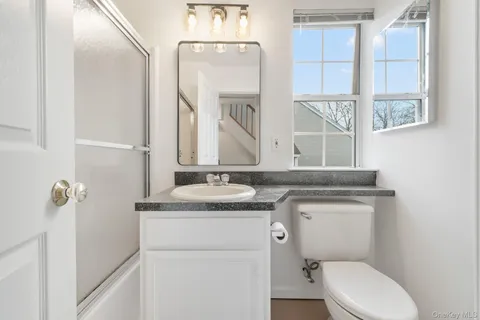 a bathroom with a granite countertop toilet sink and mirror