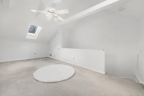an empty room with a chandelier fan and windows