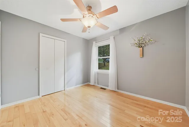 an empty room with windows and ceiling fan