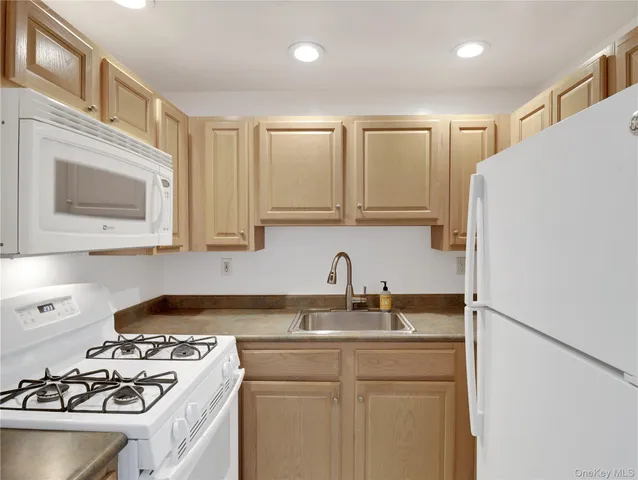 a kitchen with stainless steel appliances granite countertop a sink stove refrigerator and cabinets