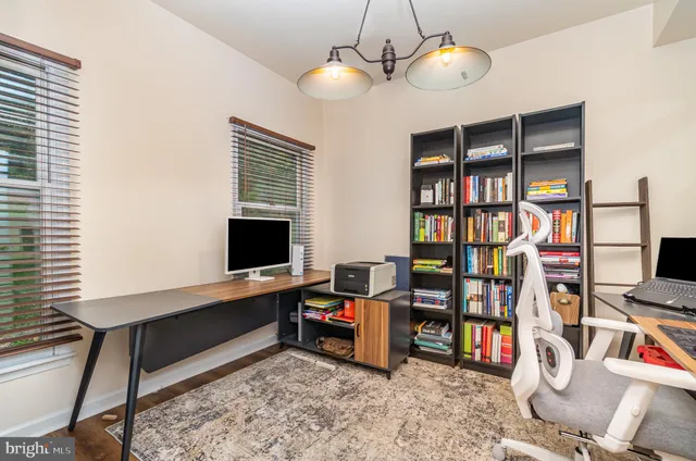a view of a workspace with bookshelf and a window