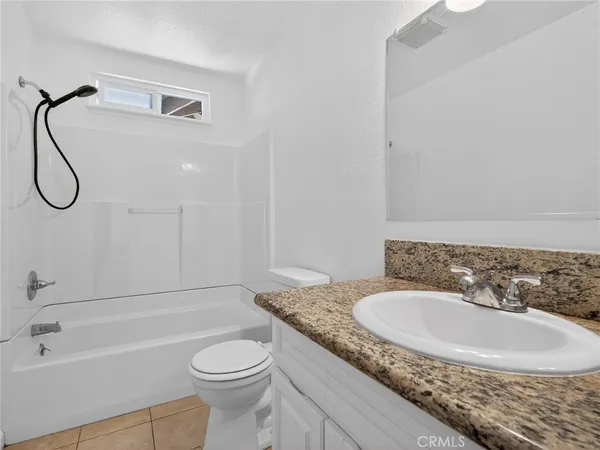 a bathroom with a granite countertop sink and a toilet