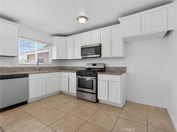 a kitchen with granite countertop white cabinets and stainless steel appliances