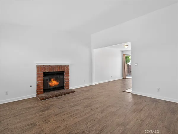 an empty room with wooden floor fire place and windows