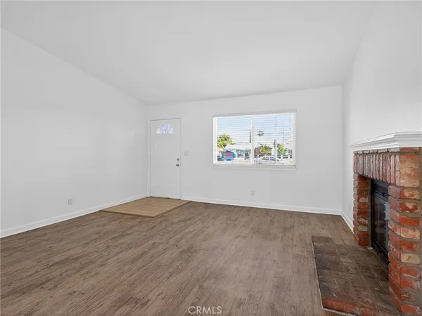 an empty room with windows fireplace and wooden floor