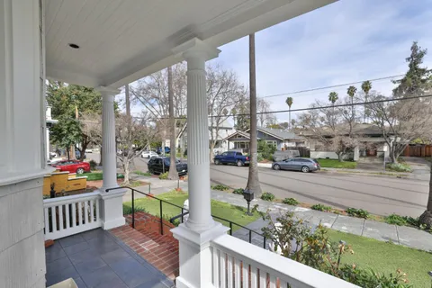 a view of a patio with a table and chairs under an umbrella with a small yard