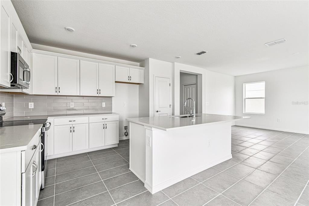 9106 Optimist Way Palmetto, FL 34221 - Photo 4 of 28 a large white kitchen with a stove a sink a window and white cabinets