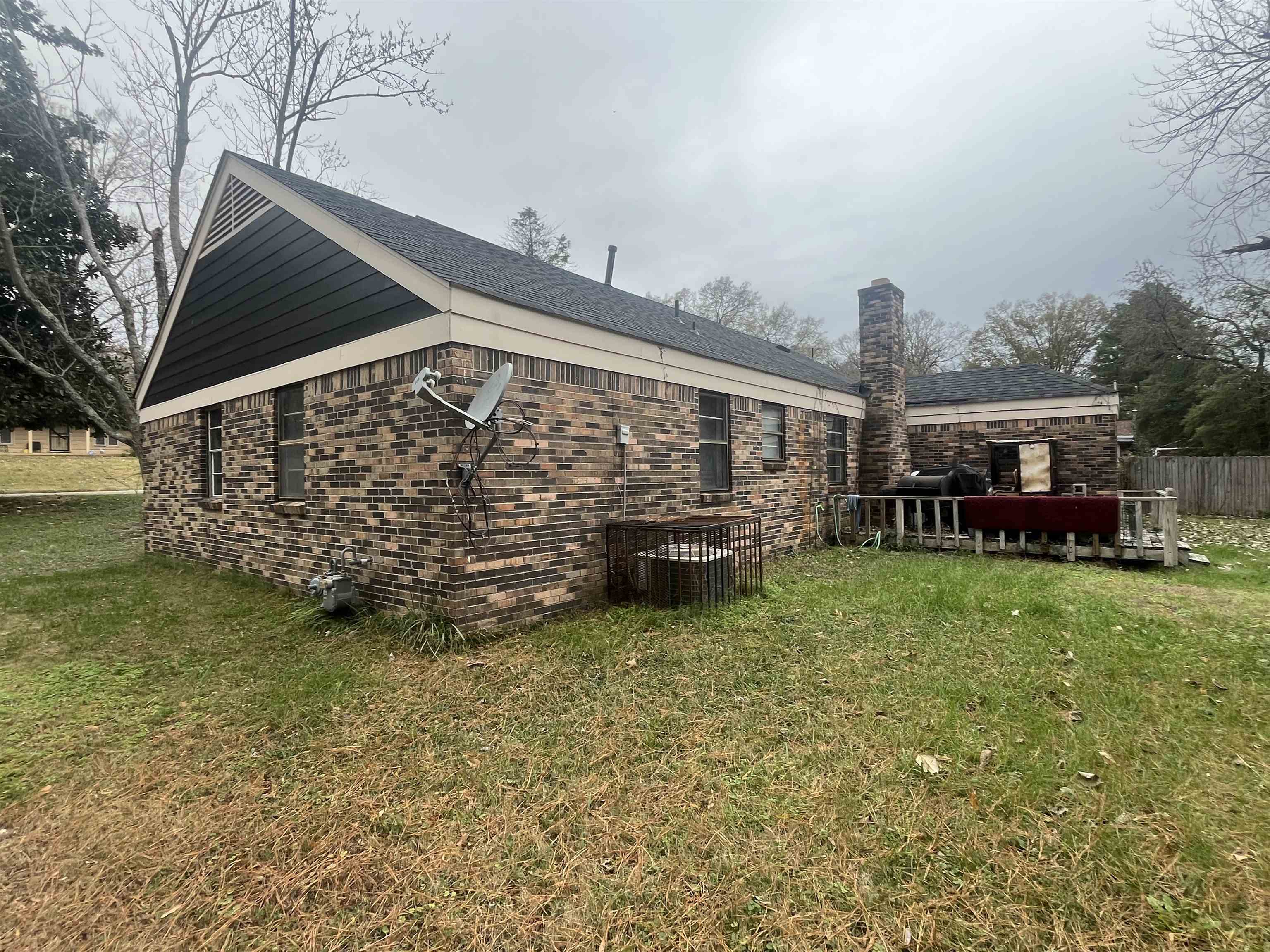3010 Falkirk Road Memphis, TN 38128 - Photo 14 of 15 View of property exterior featuring a lawn, brick siding, a chimney, and a wooden deck