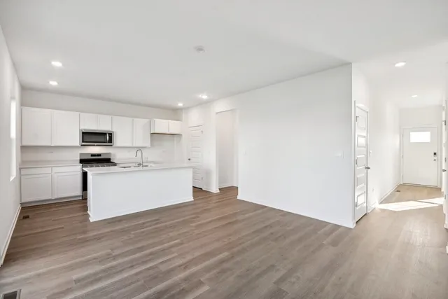 a kitchen with a refrigerator a stove and white cabinets
