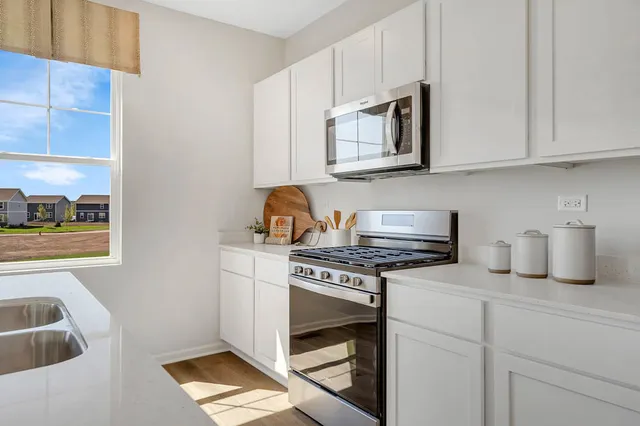 a kitchen with stainless steel appliances granite countertop a stove a sink and a microwave