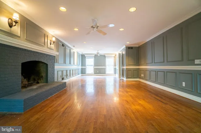a view of an empty room with wooden floor and a fireplace