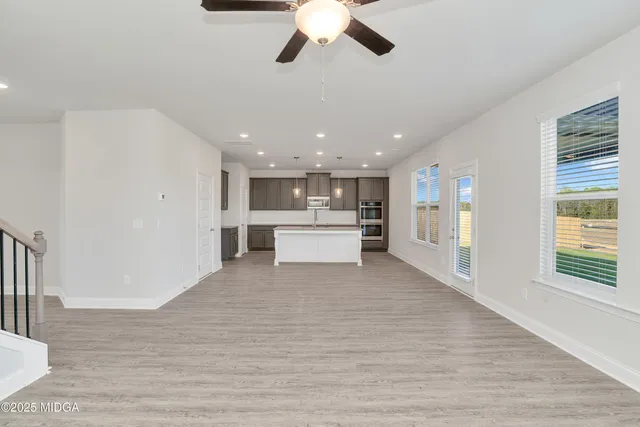 a view of a kitchen with a refrigerator a ceiling fan and wooden floor