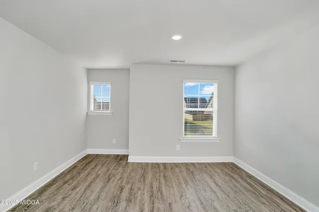 an empty room with wooden floor and windows