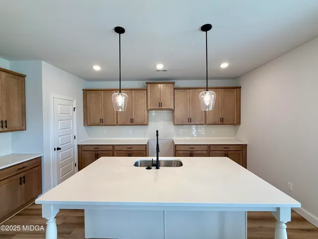 a kitchen with kitchen island a sink stainless steel appliances and chairs