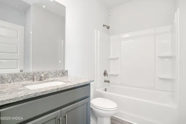 a bathroom with a granite countertop sink a toilet and bathtub