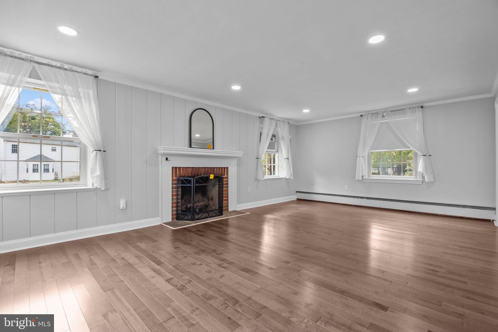 1434 Holcomb Road Huntingdon Valley, PA 19006 - Photo 10 of 49 an empty room with windows fireplace and wooden floor