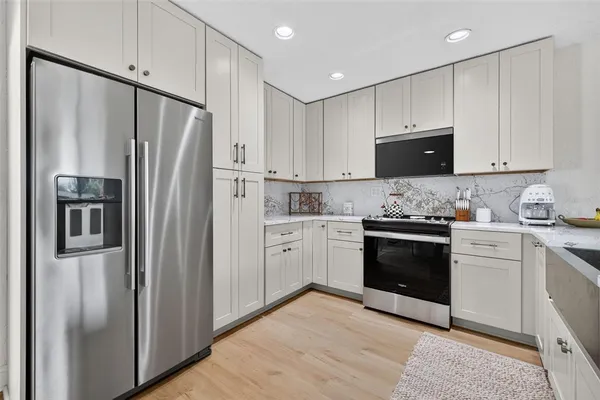 a kitchen with granite countertop white cabinets and stainless steel appliances
