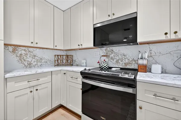 a kitchen with white cabinets and black appliances