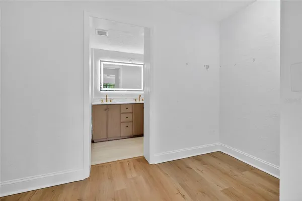a view of an empty room with closet and wooden floor