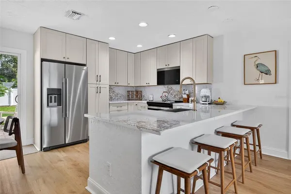 a kitchen with stainless steel appliances a refrigerator a stove a sink a dining table and chairs