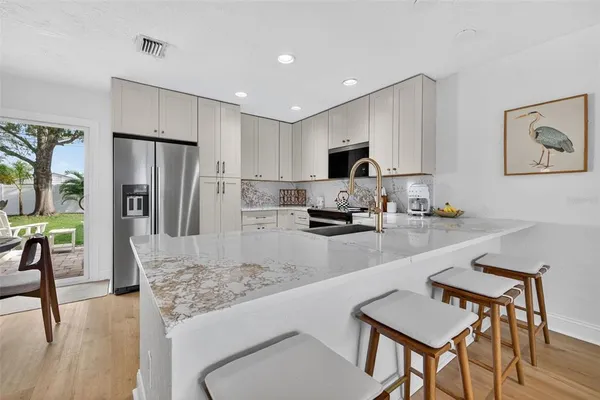 a kitchen with stainless steel appliances granite countertop a refrigerator a stove a sink a dining table and chairs