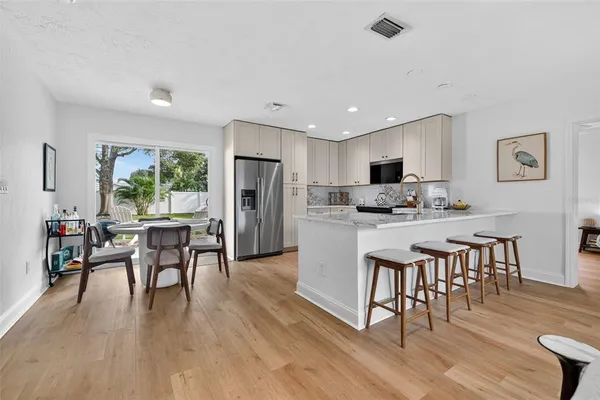 a kitchen with kitchen island wooden floor center island dining table and stainless steel appliances