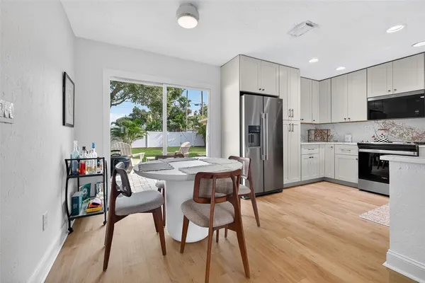 a kitchen with stainless steel appliances a dining table chairs refrigerator and sink