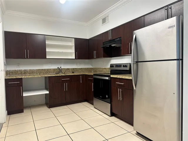 a kitchen with granite countertop a refrigerator and a stove top oven