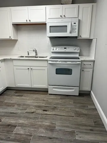 a kitchen with granite countertop white cabinets and white appliances