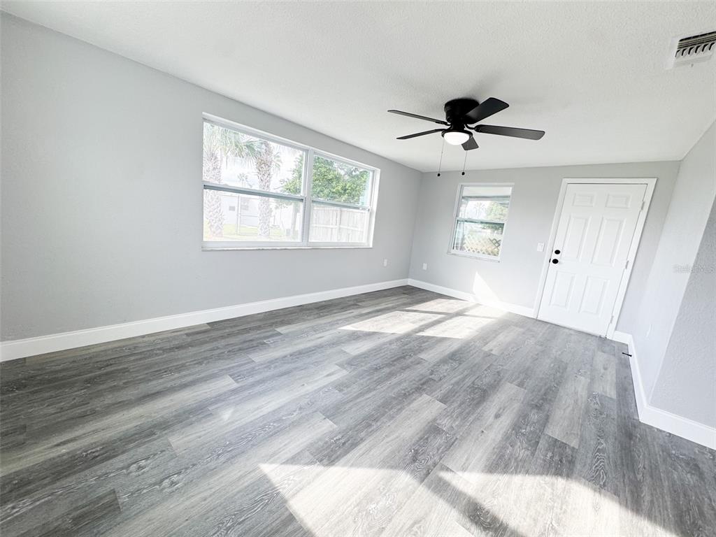 10805 Fillmore Avenue Port Richey, FL 34668 - Photo 15 of 32 an empty room with wooden floor ceiling fan and windows