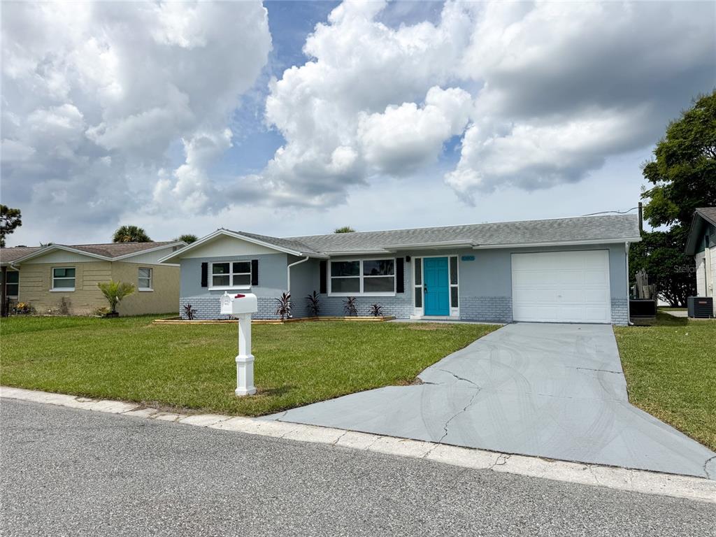 10805 Fillmore Avenue Port Richey, FL 34668 - Photo 3 of 32 a front view of a house with a garden and trees