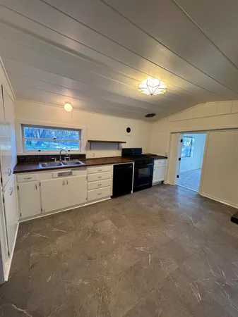 a large white kitchen with stainless steel appliances granite countertop a stove and a sink