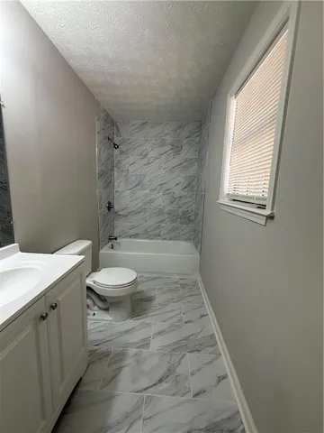 a bathroom with a granite countertop toilet a sink and a mirror