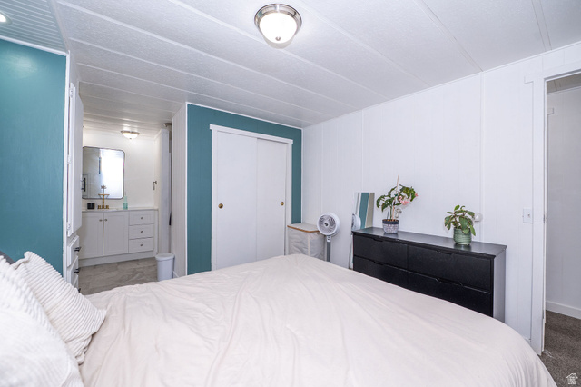 2600 North Hill Field Road, Unit 5 Layton, UT 84041 - Photo 15 of 33 Bedroom featuring a full-height accent wall, white paneled walls, and a recessed sliding closet