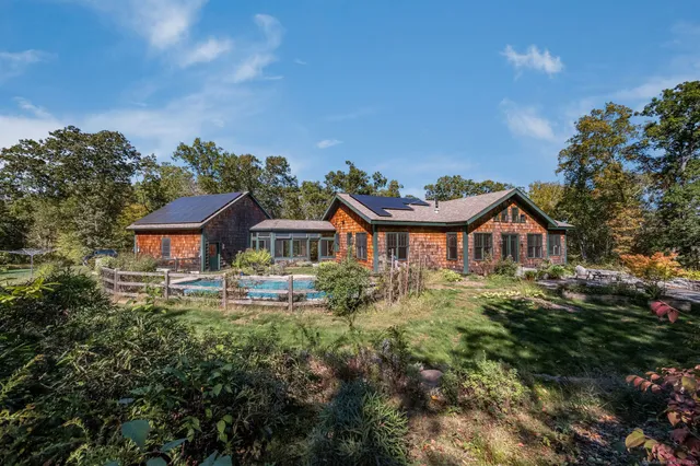 a view of a big house with a big yard plants and large trees
