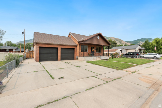673 East 700 South Springville, UT 84663 - Photo 3 of 43 Brick residence featuring a covered front porch with iron railings, a two-car garage, and a concrete driveway