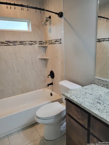 a bathroom with a granite countertop bathtub shower sink vanity and toilet
