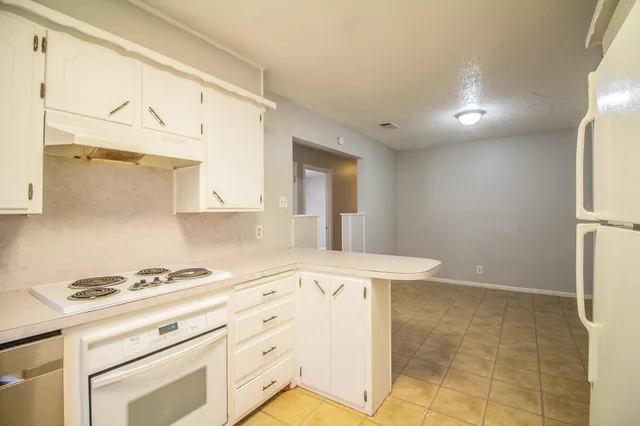 a kitchen with granite countertop white cabinets and white appliances