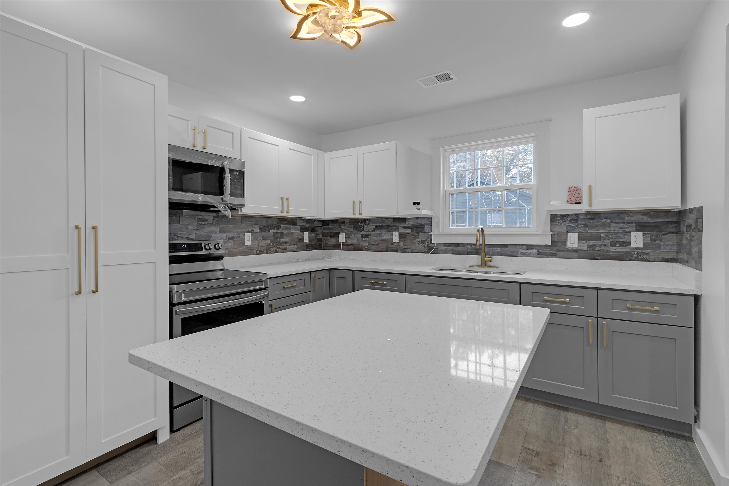 2881 Tutwiler Avenue Memphis, TN 38112 - Photo 8 of 23 Kitchen featuring gray cabinets, light stone counters, appliances with stainless steel finishes, white cabinetry, and a center island