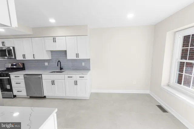 a kitchen that has a lot of white cabinets and stainless steel appliances
